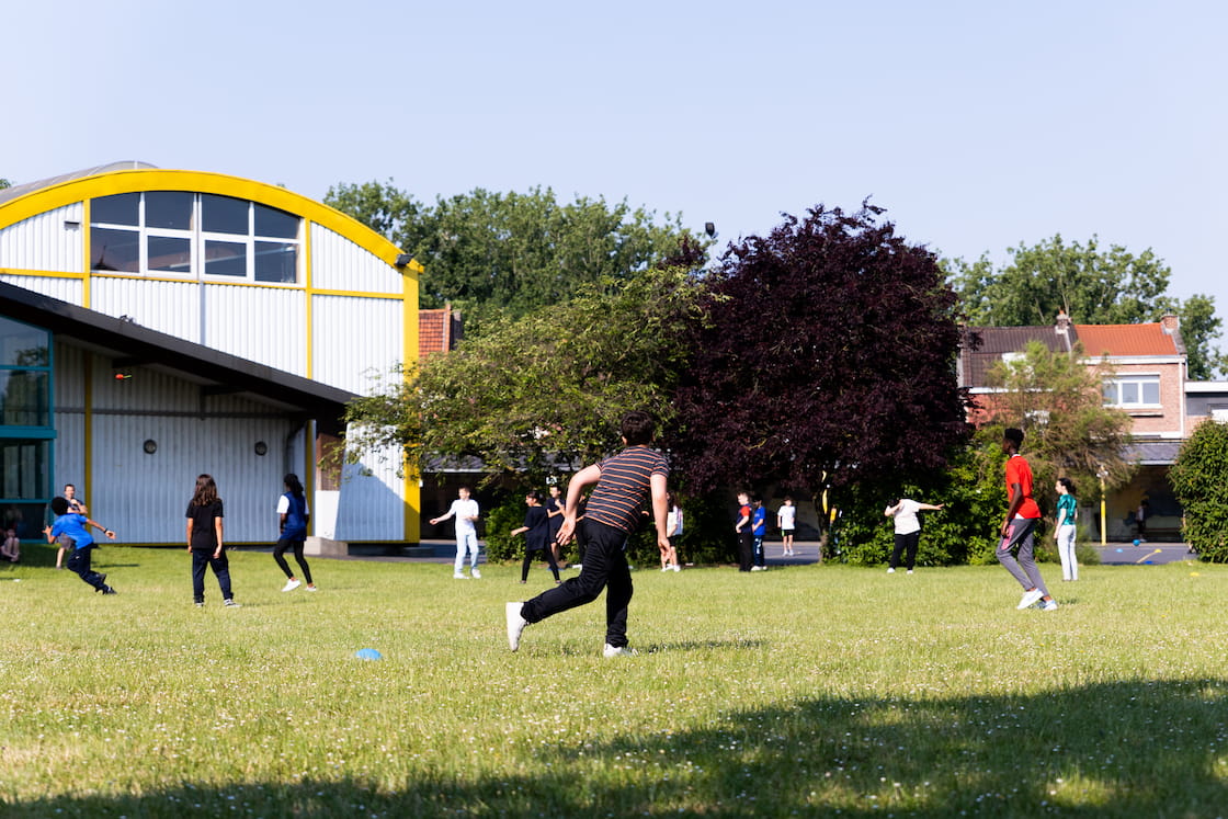 Des enfants pratiquent une activité sportive collective sur la pelouse.